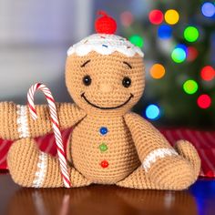 a crocheted gingerbread man holding a candy cane on top of a table