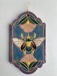 a stained glass hanging decoration with a bee on it's back and flowers in the center