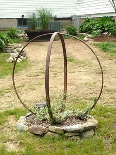 an outdoor sculpture in the middle of a yard with grass and rocks around it,