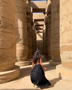 a woman sitting on the ground in front of an egyptian temple