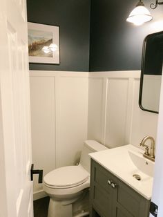 a white toilet sitting next to a sink in a bathroom under a framed picture on the wall