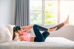 a woman laying on top of a bed with her legs up and wearing leggings