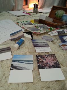 many pictures and papers are spread out on the floor next to an open box with a candle