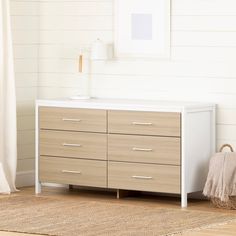 a white dresser sitting next to a window in a room with wood floors and walls