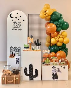 an assortment of balloons and decorations on display in front of a white wall with a cactus theme