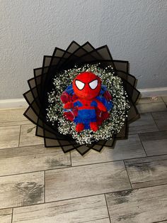 a spider - man centerpiece on the floor in front of a wall with white flowers