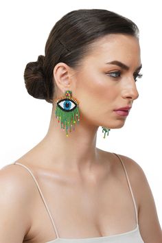 a woman wearing earrings with an evil eye on it's side and green tassels