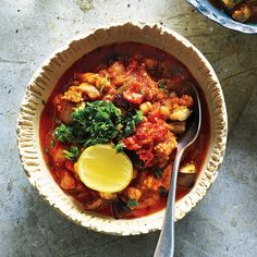 a bowl of food with a spoon in it and some other dishes on the table