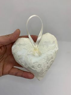 a hand holding a white heart shaped ornament