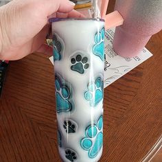 a person is holding a lighter with blue and white paw prints on it, next to a remote control