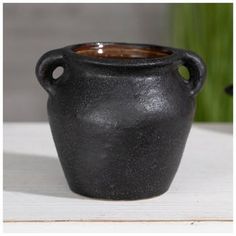 a black vase sitting on top of a white table