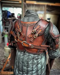 the back of a man's leather armor with chains and buckles on it