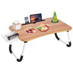 a wooden table with two plates of food on it and an open laptop sitting on top