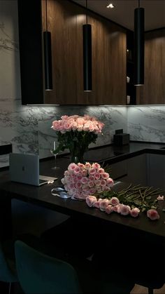 flowers are arranged on the table in front of a laptop and some lights above it