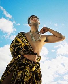 a man in a black and yellow dress with his hand on his hip looking up into the sky