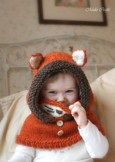 a small child wearing a knitted hat and scarf with a fox design on it