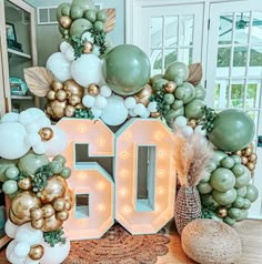 the number 50 sign is surrounded by balloons and greenery in gold, white and green colors