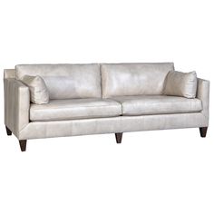 a white leather couch with two pillows on it's back and armrests