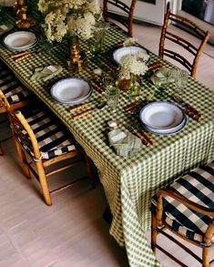 the table is set with green and white checkered cloths, place settings, and flowers