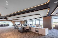 an office with wooden flooring and white desks in the center, along with large windows