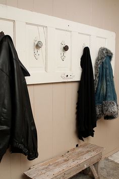 a coat rack with coats hanging on it next to a wooden bench and coat hooks