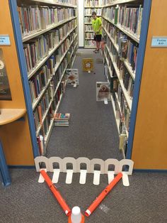 a library with bookshelves and an obstacle course in the aisle for children to play