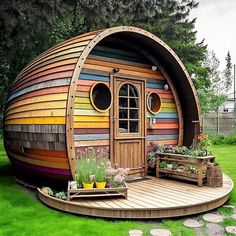 a colorfully painted dome shaped house in the middle of a grassy area with benches and potted plants