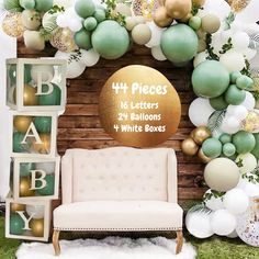 a white couch sitting under a green and gold balloon arch