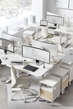 an office cubicle with multiple computer screens and desks