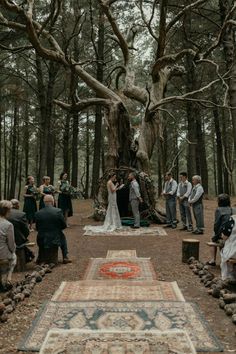 a couple getting married in the woods by their wedding ceremony area with rugs on the ground