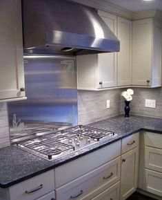 a stove top oven sitting inside of a kitchen next to white cupboards and drawers