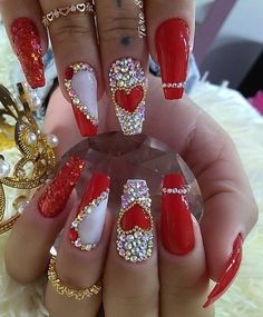 a person with red and white nail polish on their nails, holding a crystal ring