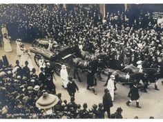 an old black and white photo of people being carried by horses in a parade on the street