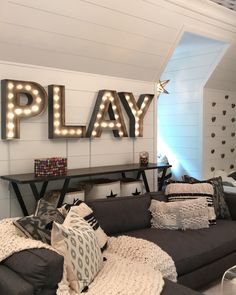 a living room filled with lots of furniture next to a play sign on the wall