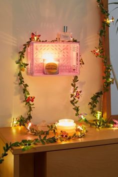 a table topped with a lit candle next to a wall covered in vines and leaves