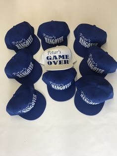 six hats are arranged in a circle on a white surface, one is blue and the other has white lettering