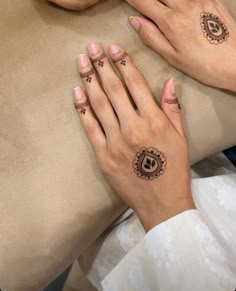 two hands with henna tattoos on their fingers and the other hand is holding a pillow