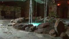 there is a large waterfall in the middle of this indoor swimming pool that's surrounded by rocks and boulders