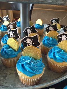 cupcakes decorated with blue frosting and pirate flags on a silver platter