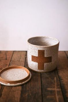 a white and brown bowl sitting on top of a wooden table next to a plate