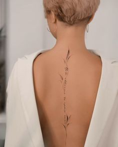 the back of a woman's neck with tattoos on her upper and lower back