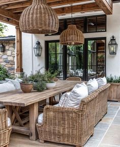 an outdoor dining area with wicker furniture and hanging lights over the table, surrounded by potted plants