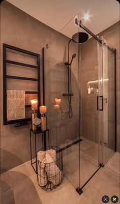 a bathroom with a walk in shower next to a candle holder and two towels on the floor