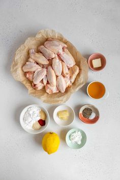 ingredients for chicken wings laid out on a white counter top, including eggs, butter, and seasonings