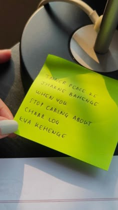 a hand holding a yellow sticky note with writing on it