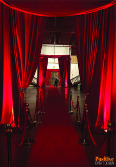 a red carpeted entrance way to an event venue with red drapes and rope barriers