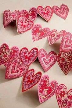 many pink and red hearts are arranged on a white surface with one being cut out