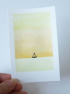 a person holding up a card with a small boat on it