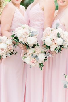 four bridesmaids in pink dresses holding bouquets with white and pink flowers on them