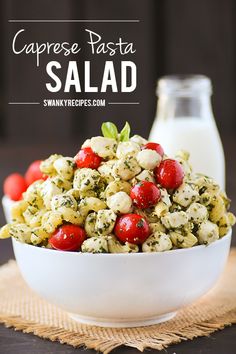 caprese pasta salad with tomatoes and mozzarella in a white bowl next to a bottle of milk